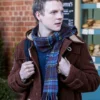 The Portable Door 2023 Patrick Gibson Brown Coat closeup.webp